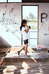 Side view of girl walking against wall