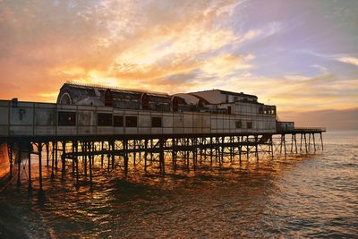 Built structure by sea against orange sky