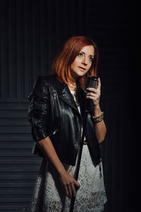 Full length of young woman standing against black background