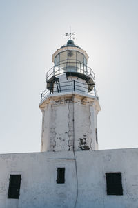 Low angle view of lighthouse by building against clear sky