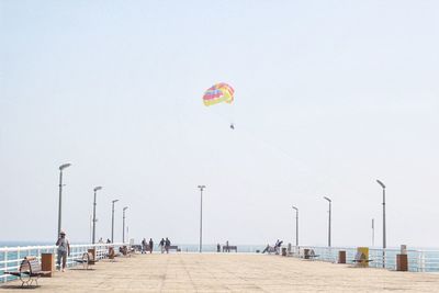 People on pier over sea against clear sky