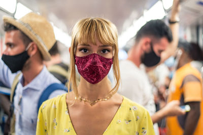 Portrait of woman wearing mask standing in bus