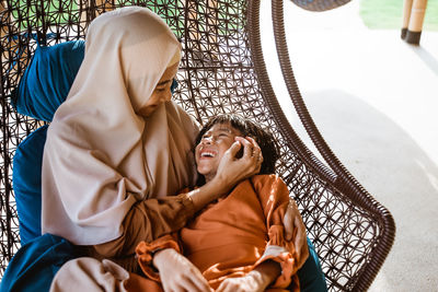 Mother and daughter sitting on hammock