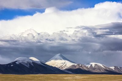 Scenic view of snow covered mountains against cloudy sky