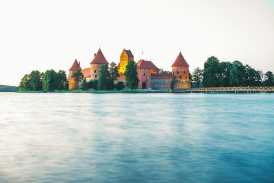 View of buildings by lake against clear sky