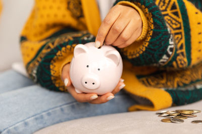 Midsection of woman holding piggy bank on table