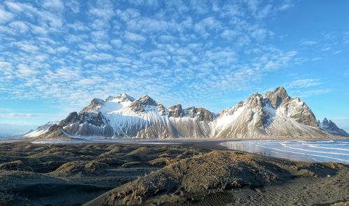 Panoramic view of people on snowcapped mountain against sky