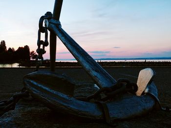 Metallic structure on beach against sky during sunset