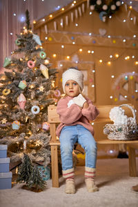 Portrait of cute girl playing with christmas tree at home