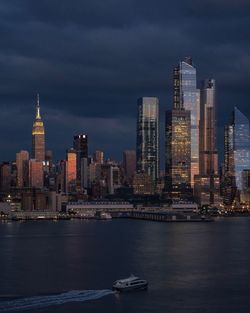 Sea by modern buildings against sky in city