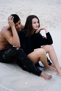 Portrait of young couple sitting at beach