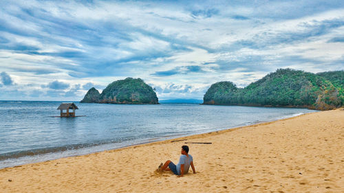 Rear view of man looking at sea against sky