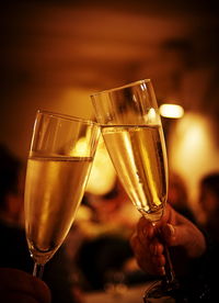 Close-up of champagne flutes toasting at night