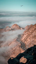 Bird flying over mountain against sky