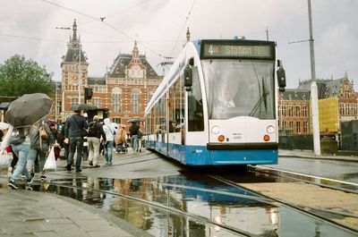People on wet street in city during rainy season