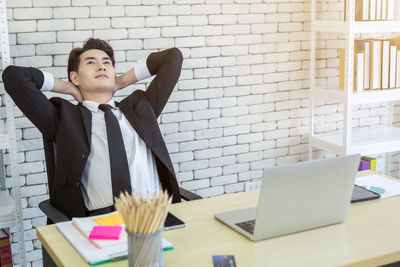 Mid adult man using laptop on table against wall