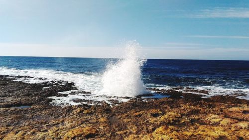 Waves splashing on sea against sky