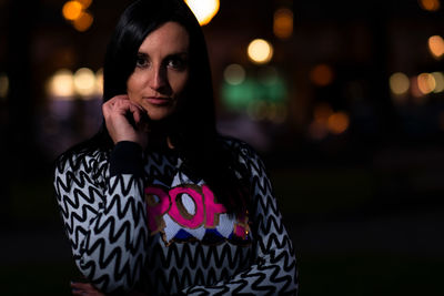 Portrait of woman standing on illuminated smart phone at night