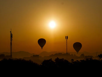 Silhouette hot air balloons against sky during sunset