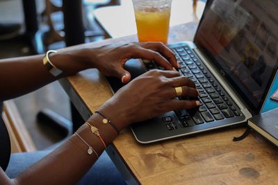 Cropped image of woman hands using laptop on table at home