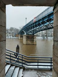 Bridge over river in city against sky