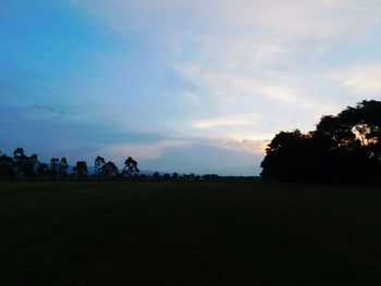 Silhouette trees on field against sky