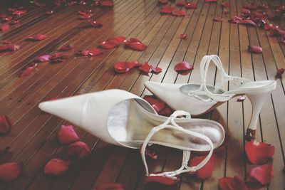 High heels and rose petals on wooden floor