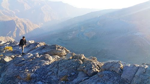 Man walking on rocks by mountain during winter