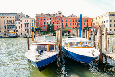 Boats moored in canal against buildings in city