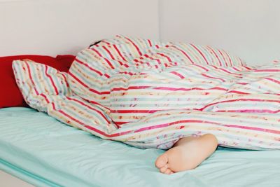 Low section of person sleeping on bed at home