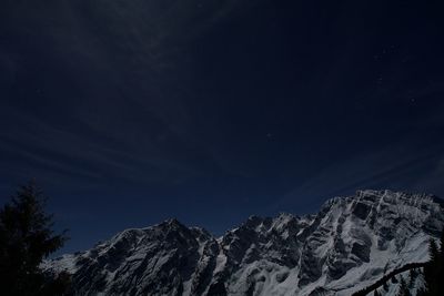 Low angle view of snowcapped mountains against clear sky at night