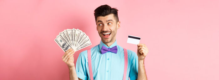 Portrait of smiling young woman standing against pink background