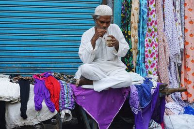 Low angle view of man holding ice cream sitting outdoors