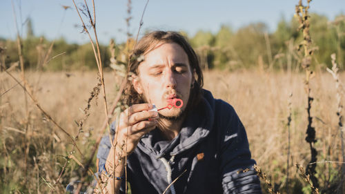 Portrait of young woman holding plant on field