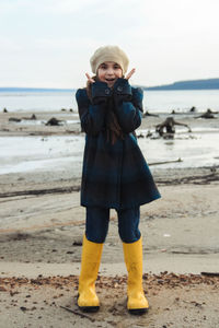 Girl in big yellow rubber boots walking at seashore