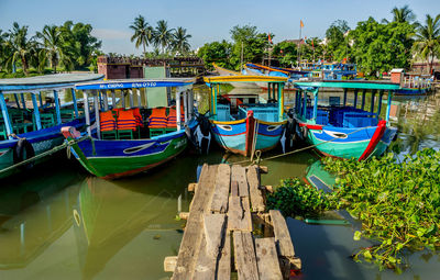 Boats moored in canal against blue sky