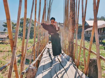Full length of asian woman standing on bamboo bridge in the garden, thailand
