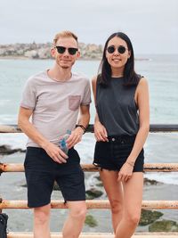 Full length of young friends standing against sea