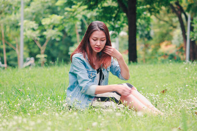 Full length of young woman sitting on land