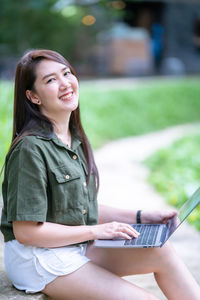 Young woman using mobile phone while sitting on table