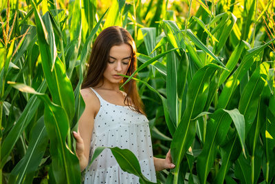 Portrait of young woman standing amidst plants