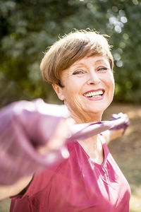 Portrait of smiling senior woman exercising with resistance band outdoors