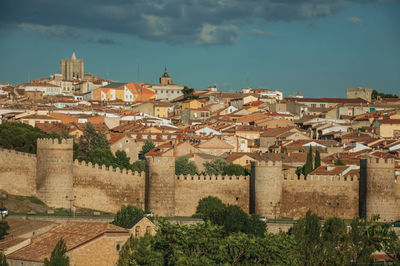 Stone towers with large wall over the hill encircling the avila houses at sunset, in spain.