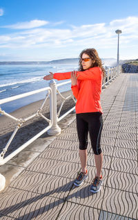 Woman standing on railing against sea