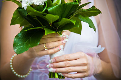 Midsection of bride holding bouquet