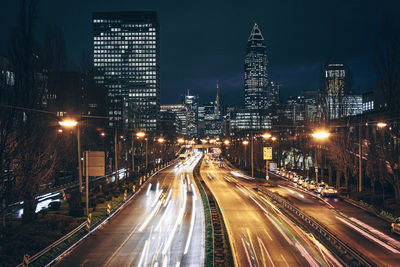 Light trails on road amidst buildings in city at night