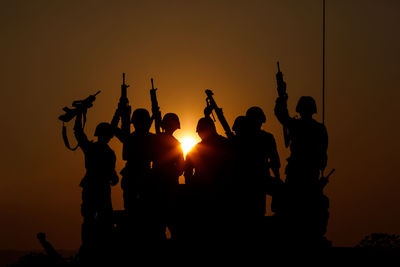 Silhouette group of special forces sodiers hold the guns on tank to indicative of their victory