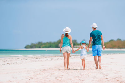 Rear view of people walking on beach