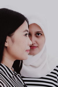 Female friends standing against white wall