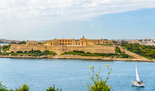 Scenic view of river by buildings against sky
